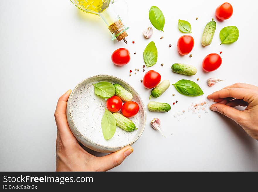 Fresh cut salad ingredients falling into white bowl on white minimal background. Ingredients for making dieting healthy vegetable salad.