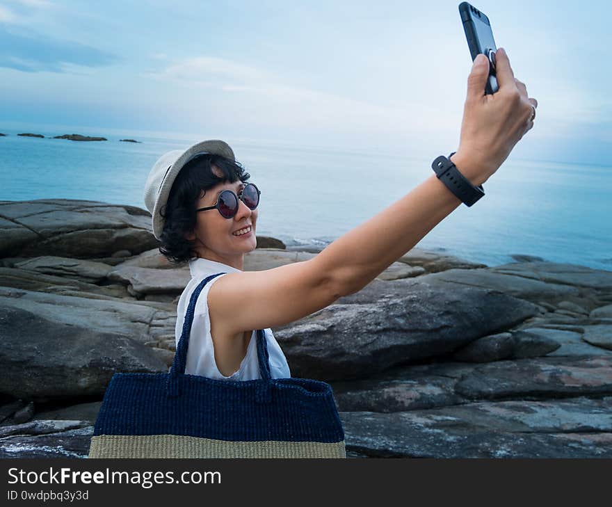 Female travelers take a picture with a smartphone in a seaside tourist spot in Thailand.