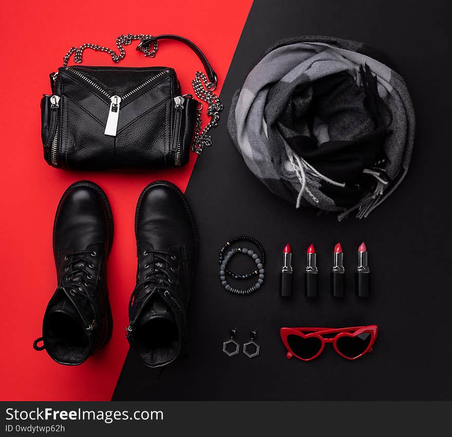 Flat lay top view bag with accessories and footwear on double red and black background