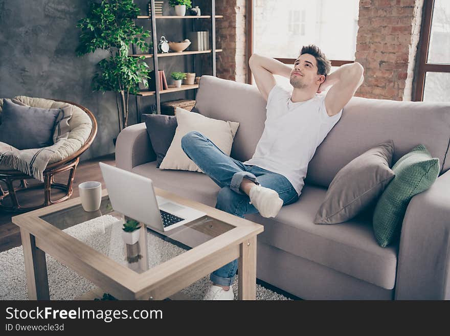 Portrait of his he nice attractive muscular dreamy guy sitting on divan resting pause break working remotely at modern