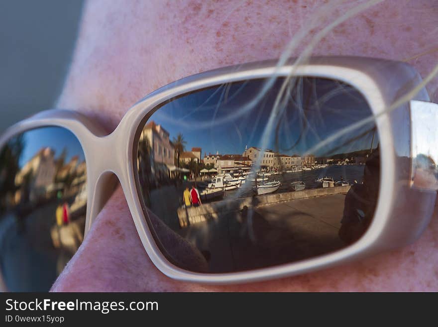 Sunglasses in the eyes of a woman and in the reflection of the glasses can see the city on the Adriatic on the island of Hvar