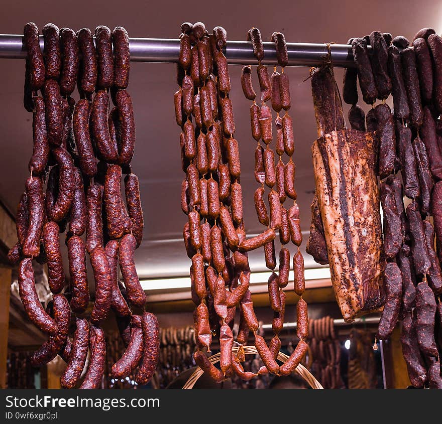 Many homemade German mix of meat specialties, speck ham sausages pile or stack on counter top, for sale, during food festival, outdoor outside marketplace, spicy and tasty fresh specialty for sale