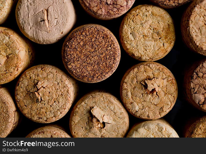 Wine corks of different sizes, standing upright on an old wooden surface.