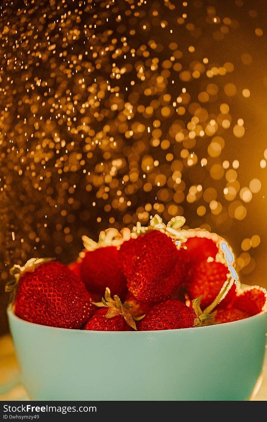 Red juicy ripe strawberries in a blue vase on a black background. Drops of water, warm sunshine, back light, vertical