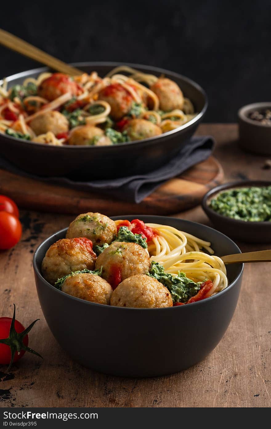 Pasta with meatballs and spinach with tomato sauce.