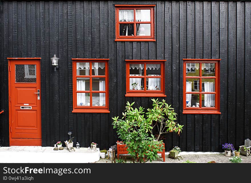 Black house with red windows and door and decorated yard