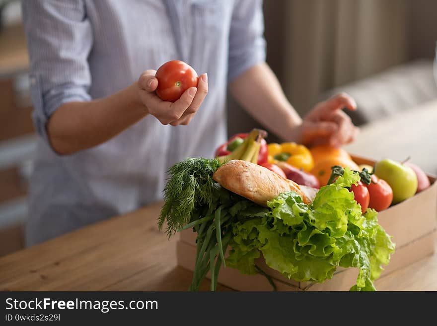 Groceries. Girl in grey homewear standing in the kitchen with groceries on the table