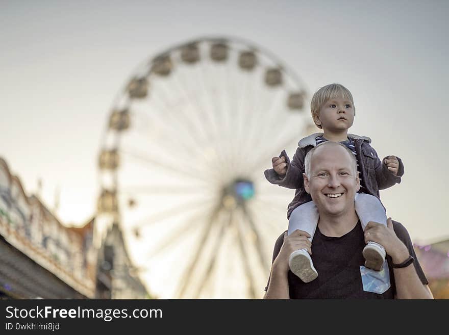 Happy father with his little piggybacked son in an amusement park. Happy father with his little piggybacked son in an amusement park