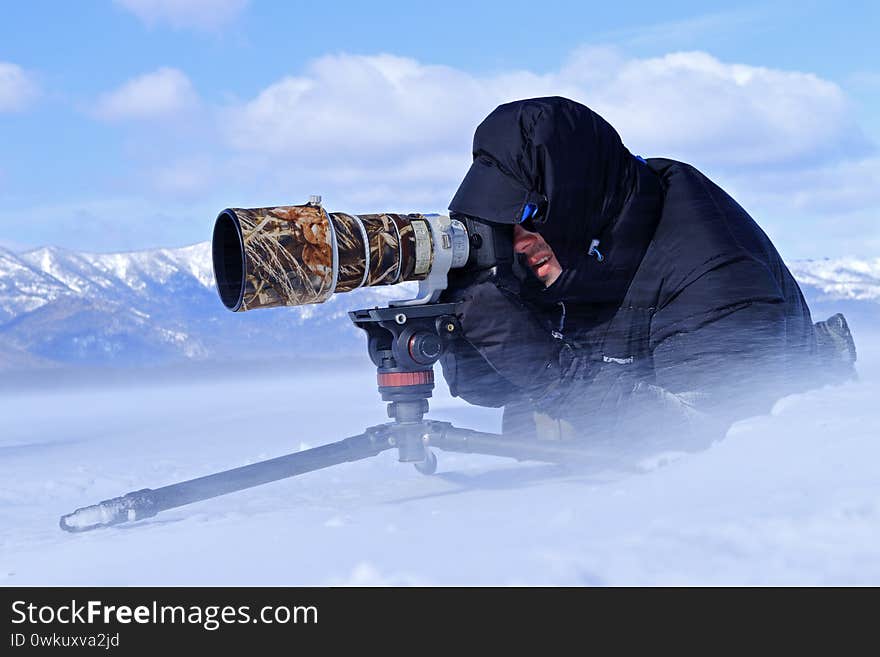 Winter photography, man in the snow with camera. Snow lake with ice in Japan. Whooper Swans, Cygnus cygnus, birds in the nature habitat, Lake Kusharo, winter scene with snow , Hokkaido, Japan