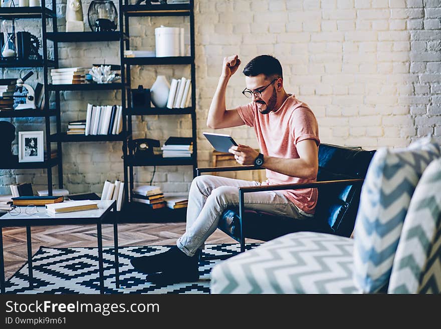 Young hipster guy sitting on comfortable chair in modern flat