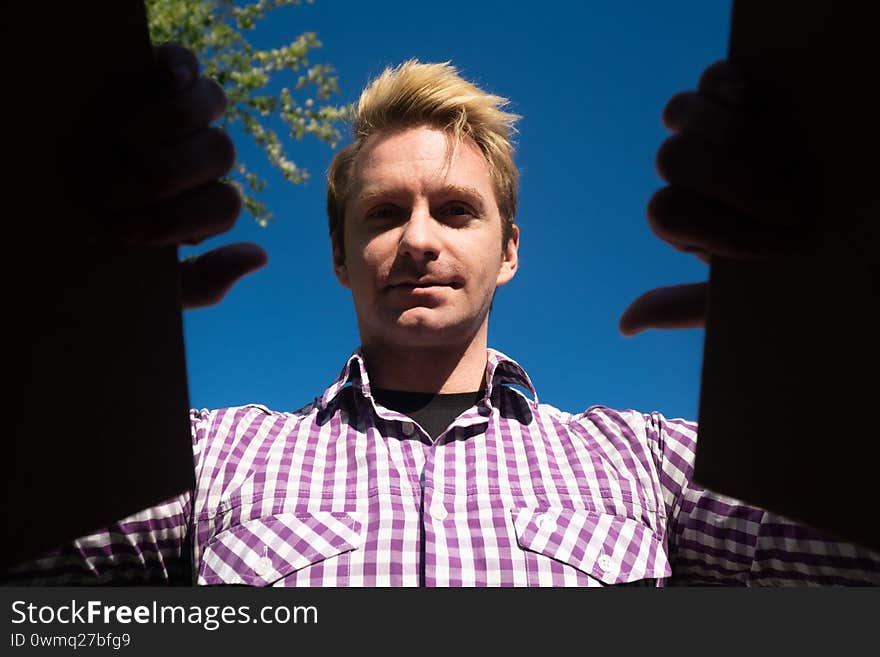 Head shot portrait of a Caucasian young man opens a paper box and rejoices. Open Air Birthday Presentation Concept.