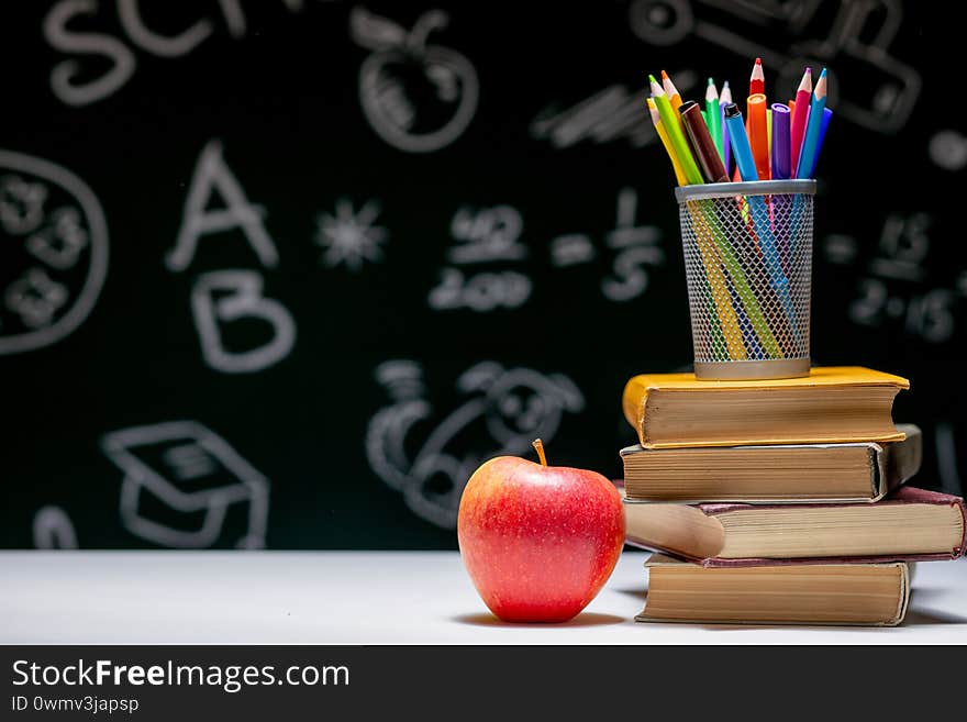 Back to school background with books, pencils and apple on white table