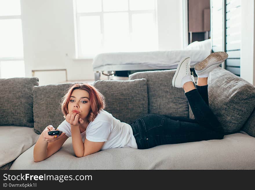 woman with remote controller watching tv at home on self isolation. woman with remote controller watching tv at home on self isolation