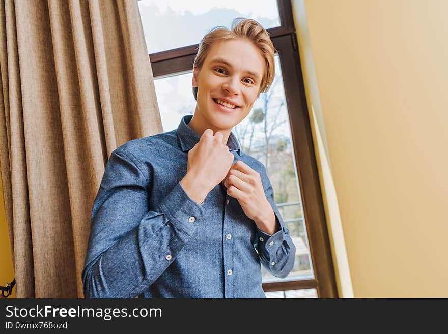 Happy young man touching blue shirt at home, end of quarantine concept