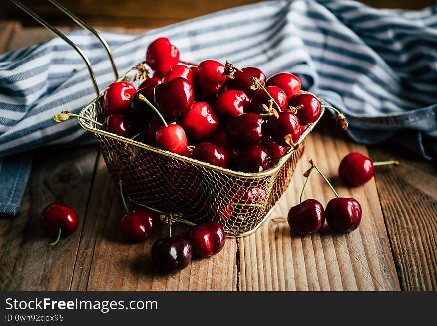 Cherries in a metal basket on a wooden table