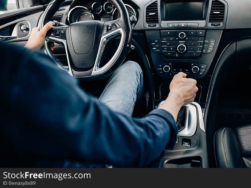 Hands of a man holding the steering wheel while driving a car