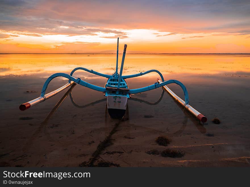 Seascape. Fisherman boat jukung. Traditional fishing boat at the beach during sunrise. Water reflection. Sanur beach, Bali