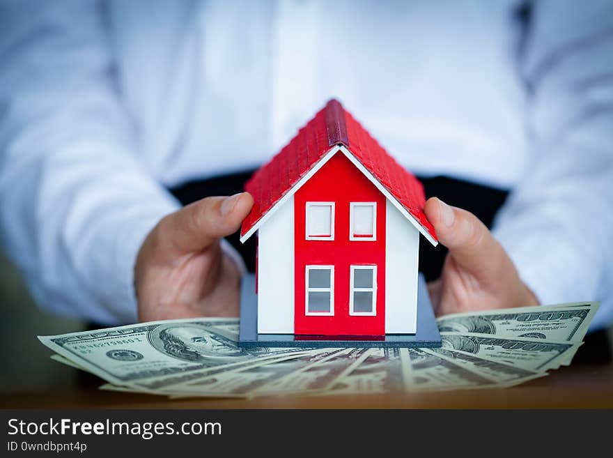 Business people holding banknotes There is a red roof house in the banknote. Real estate investment concept, mortgage, saving money for a new home, home loans with space for text input