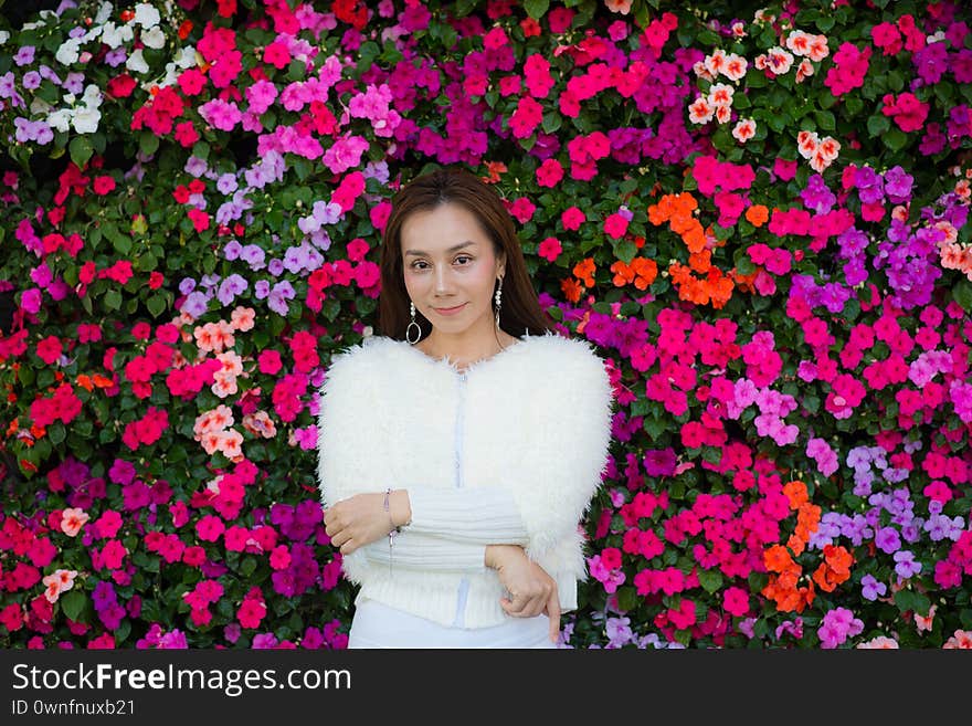 Portrait beautiful woman relaxing in flower garden. Impatiens balsamina background
