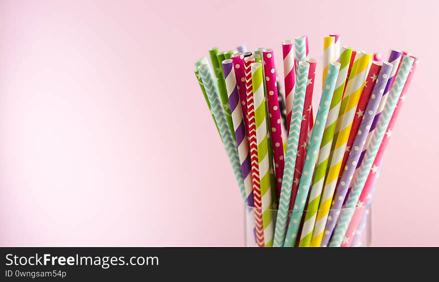 Colorful paper tubes for drinks in a glass on colored backgrounds. The concept of a party, celebration, birthday. Copy space. Colorful paper tubes for drinks in a glass on colored backgrounds. The concept of a party, celebration, birthday. Copy space