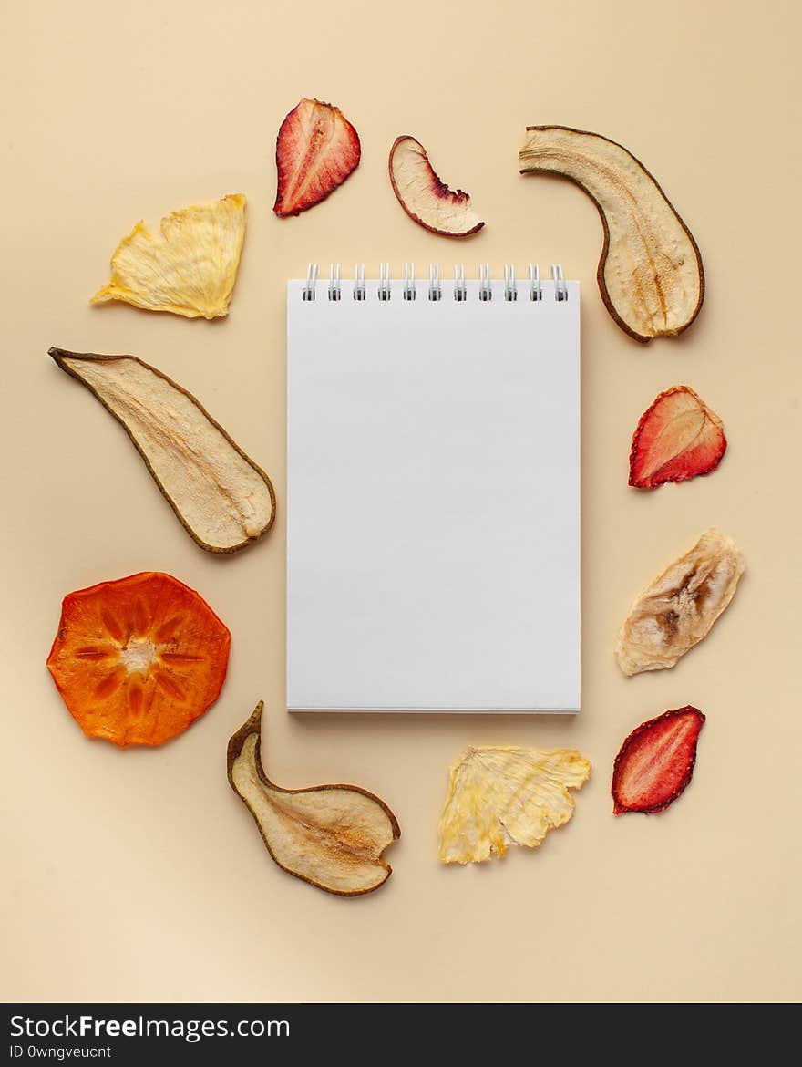 Blank notebook for text, fruit chips. The concept of a healthy diet, vegetarian food, fruit desserts. Copy space