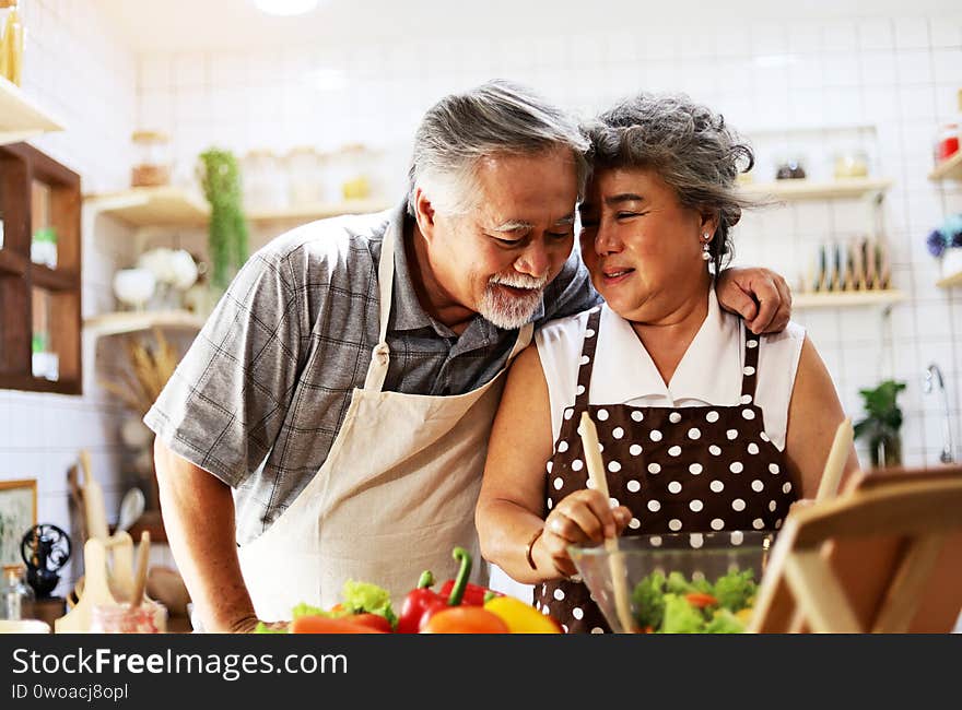 Happiness senior elderly couple having fun in kitchen with healthy food for working from home.