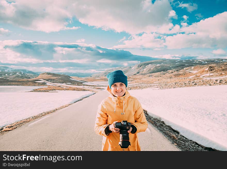 Aurlandsfjellet, Norway. Young Happy Woman Tourist Traveler Photographer Taking Pictures Photos Of Aurlandsfjellet Scenic Route Road. Norwegian Landmark And Popular Destination.