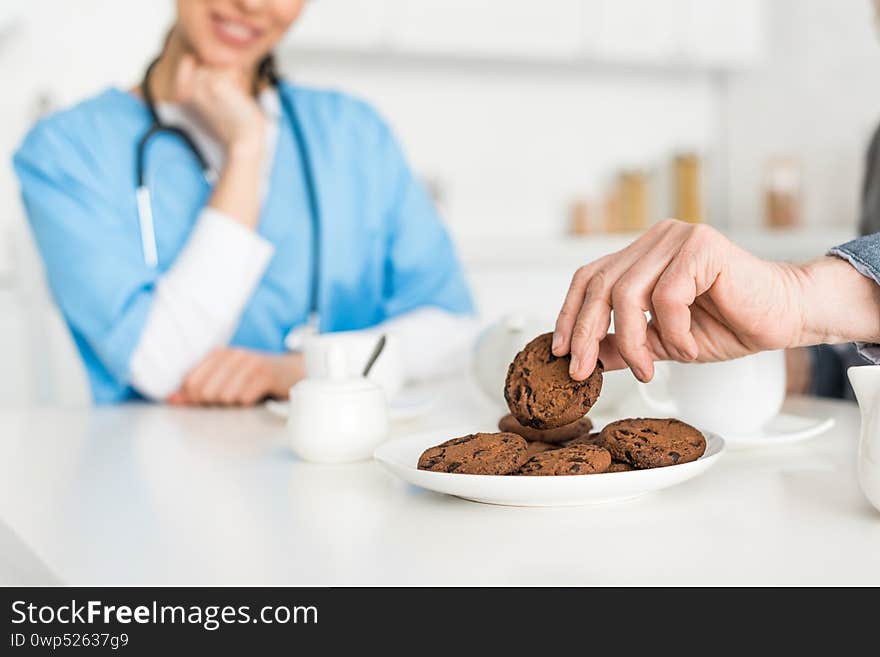 Focus of man hand with cookie and nurse on background