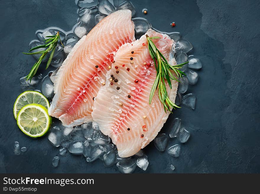 Fresh fish fillet of sea bass in ice on a dark slate background.