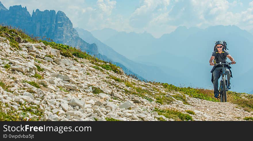Sport and Recreation. Caucasian Men Riding on Mountain Bike. Scenic Mountain Trail. Panoramic Photo