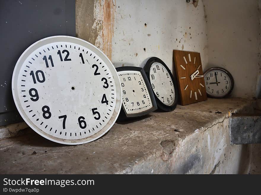 Round and square clocks against the wall, two clock dials, clock dial, many wall clocks, two old watches