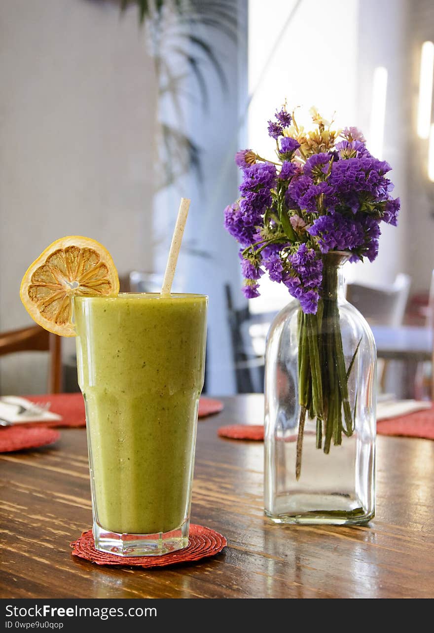 Smoothie in a Cristal glass on a wooden table, jar with flowers. Healthy care life style