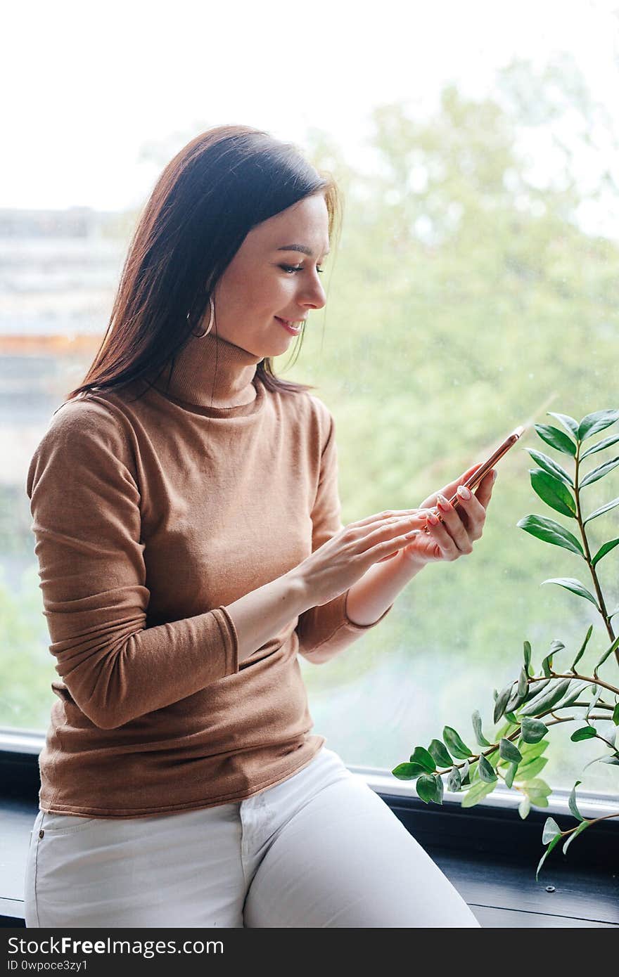 Woman using cellphone and looking window at home