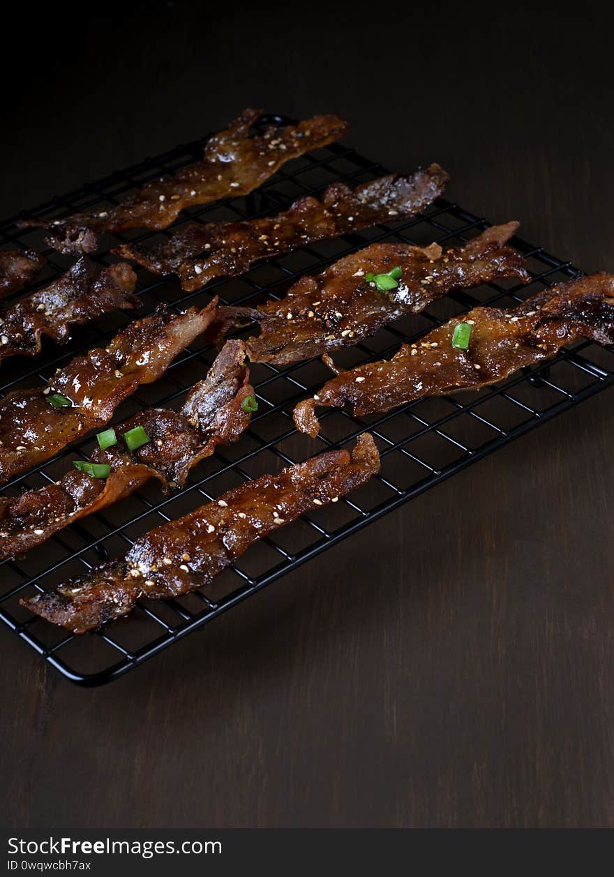 Roasted bacon in sweet maple syrup glazing topped with sesame seeds and herbs on the black lattice