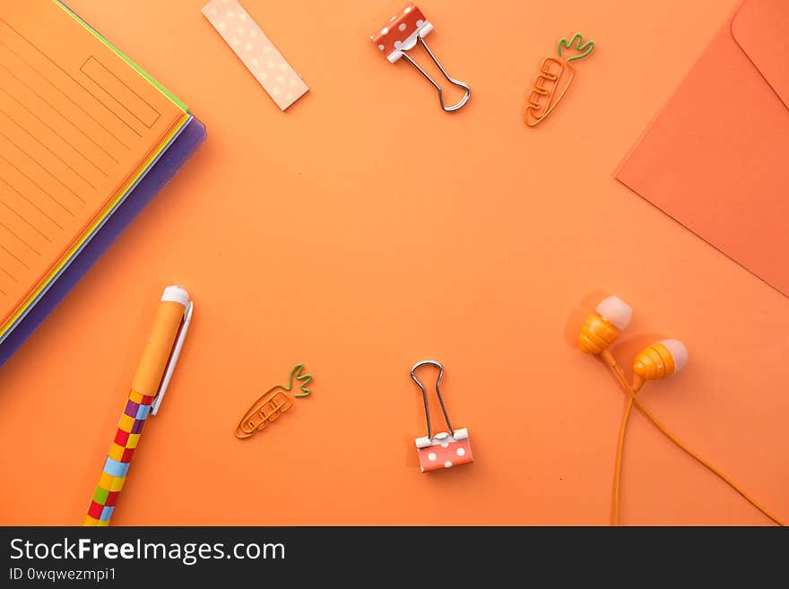 Orange notepad, envelope and stationary on orange background.