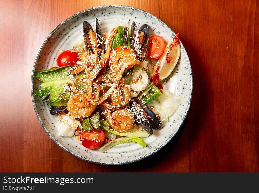 Salad of fresh seafood, mussels, shrimp, fresh vegetables and greens on a wooden background. Salad of fresh seafood, mussels, shrimp, fresh vegetables and greens on a wooden background