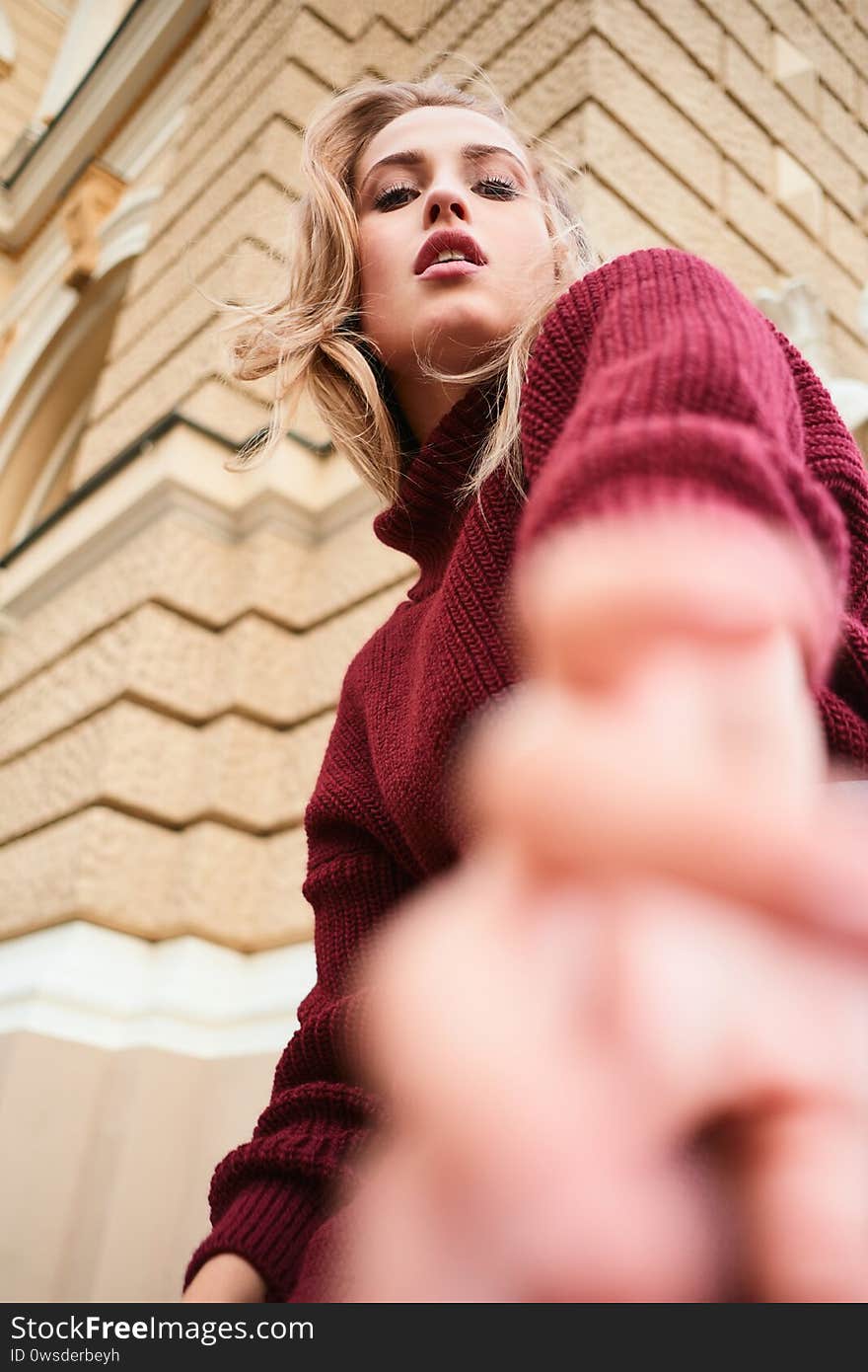 Conceptual shot of beautiful sensual blond girl in sweater dreamily posing outdoor