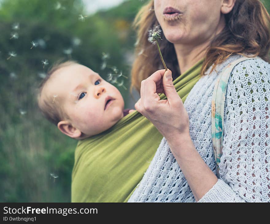 Mother with baby blowing dandelion