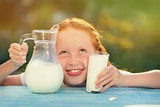 Milk Is Fresh From The Cow - A Beautiful Girl With Dairy Products. Girl Holds Glass With Fresh Milk. Happy Redhead Child In Summer Stock Image