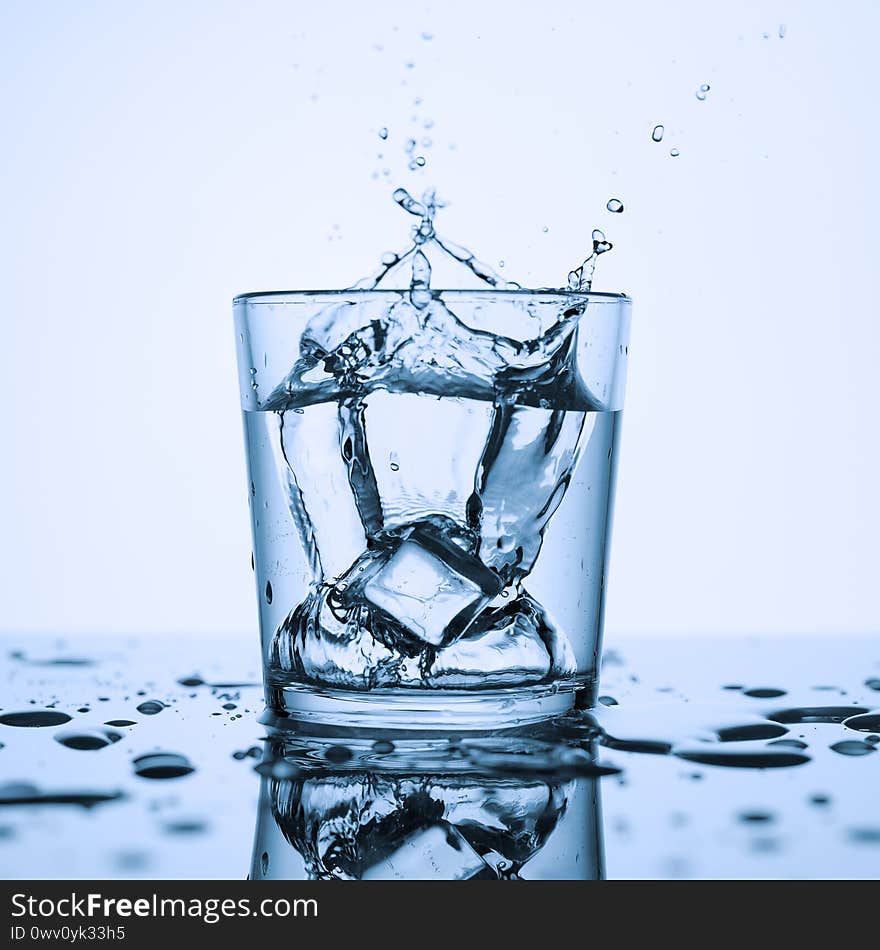 Splashes of clean water in a glass with ice, on a white background