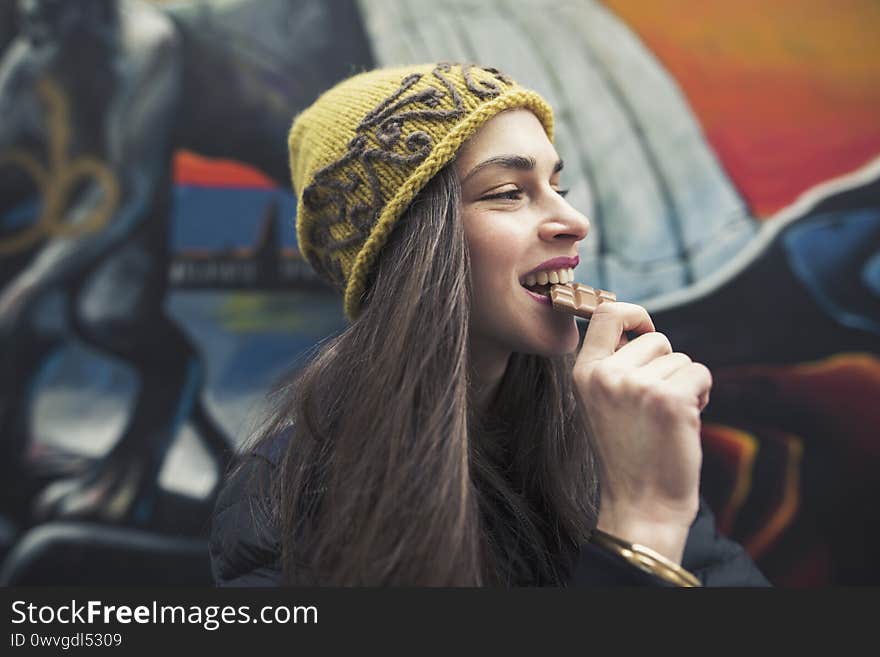 A candid image of a beautiful young woman biting a chocolate bar