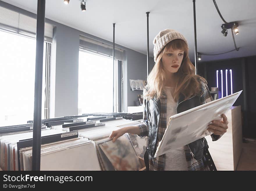 A beautiful young woman audiophile is browsing vinyl records in a store