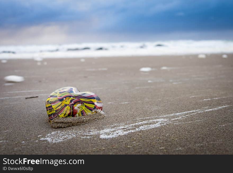 A custom glass heart made in studio staged in the sand on the beach. A custom glass heart made in studio staged in the sand on the beach