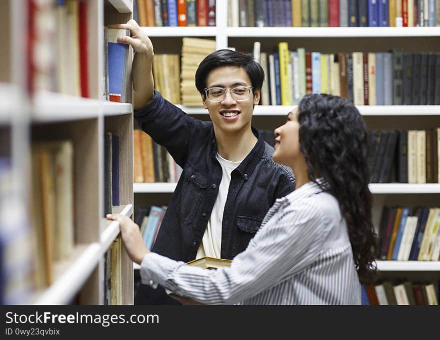 Happy japanese guy taking book at library for his girl