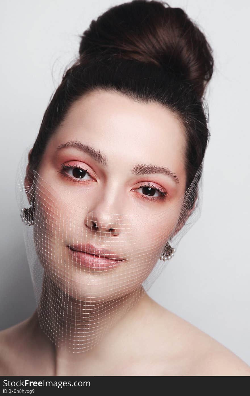 Vintage style portrait of young beautiful woman with pink makeup and fishnet mask on her face