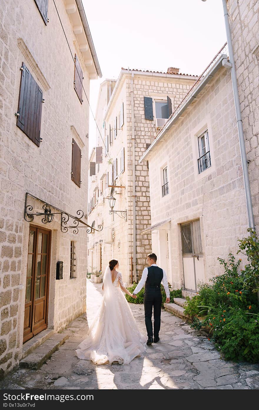 The bride and groom walk in the street among the old houses. The bride and groom walk in the street among the old houses.