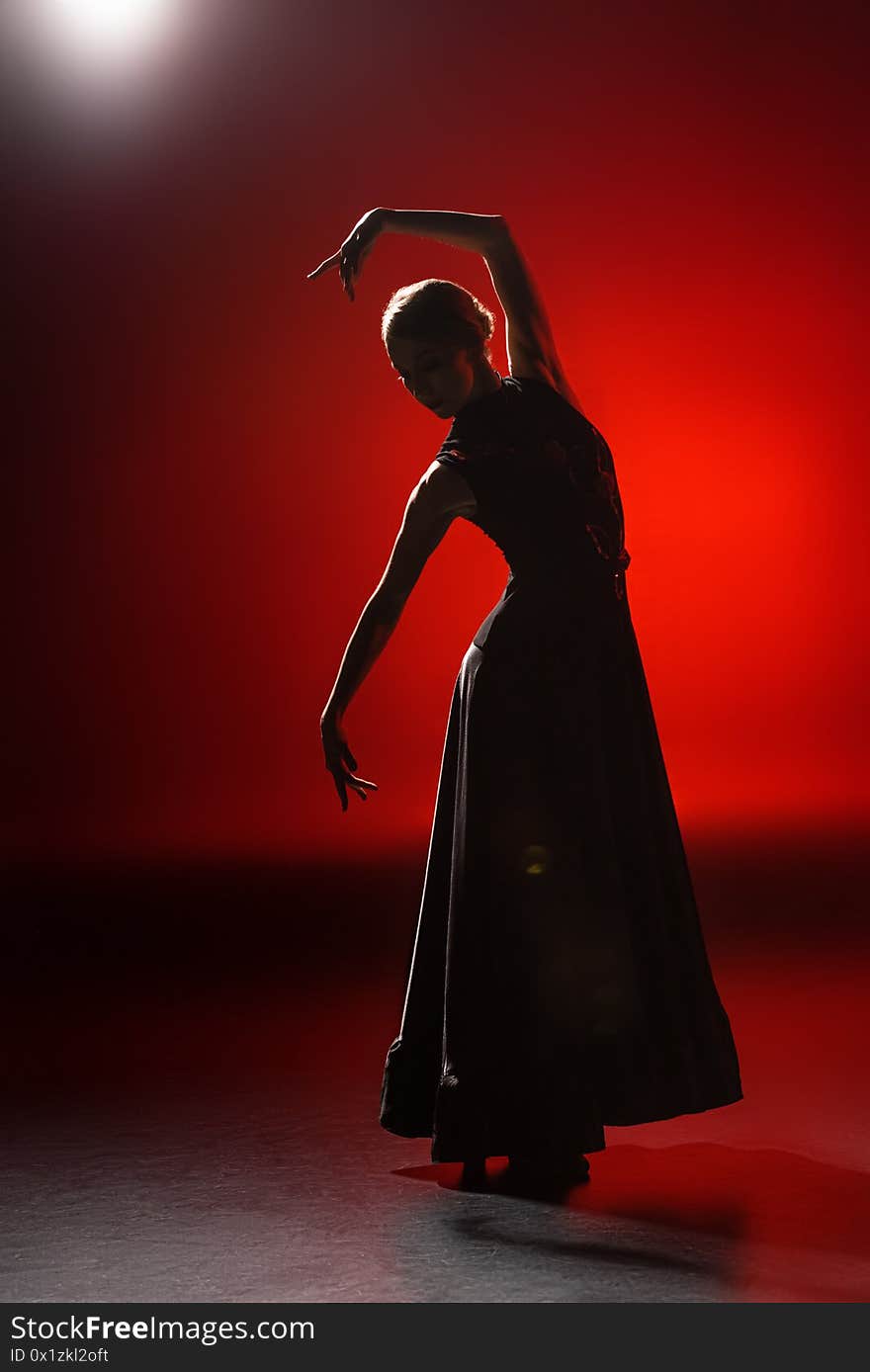 Silhouette of young woman dancing flamenco on red