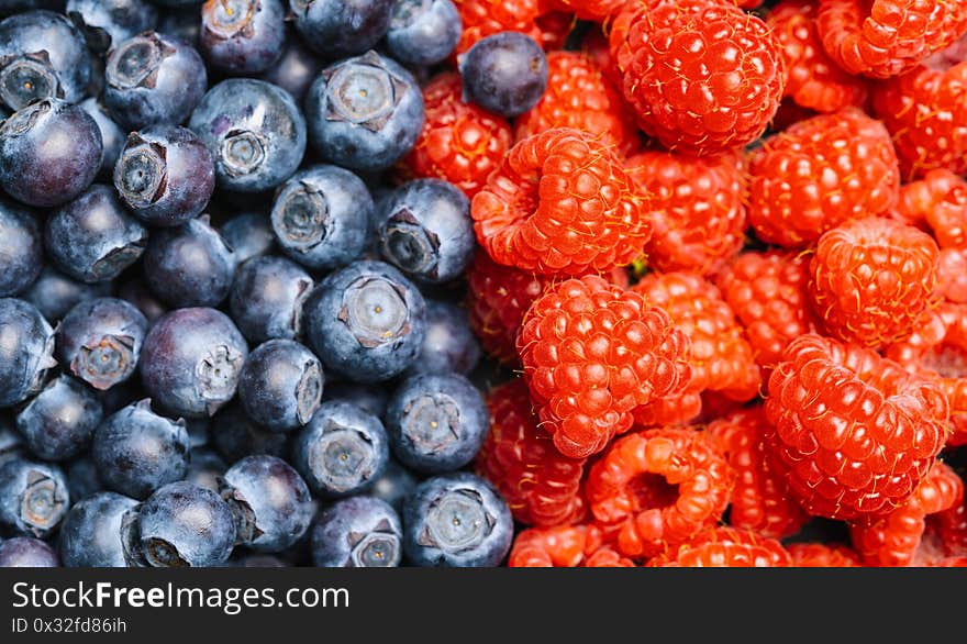 Fresh blueberries and raspberrys background or backdrop. Vegan and vegetarian concept. Macro texture of blueberry and raspberry