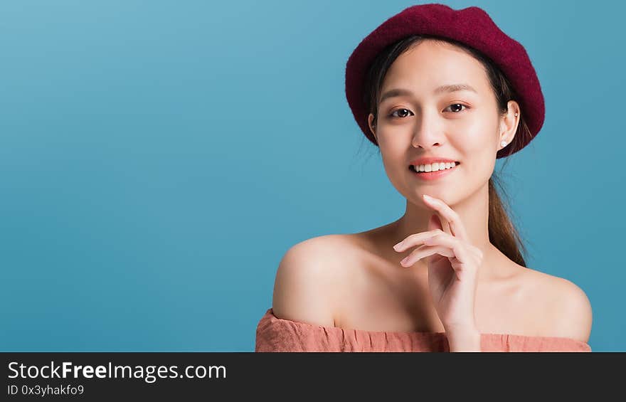 Portrait of confident beautiful asian woman with hand beside face and looking to camera isolated on blue color background with studio shot.Skincare for healthy face concept