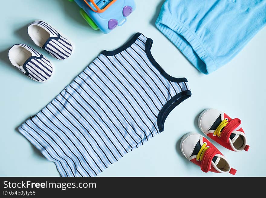 Kit of baby boy clothes, tiny shoes and toy car on blue background. Baby accessories, infancy concept.